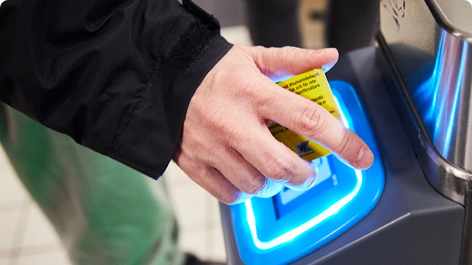 Hand som håller i ett gult kort framför en kortläsare vid tunnelbanespärr.