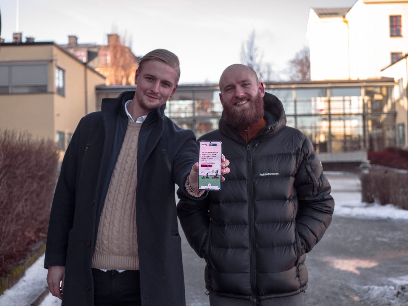 Bild på Jacob och Emil som håller upp en telefon med appen Treddy synlig